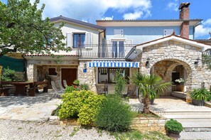 A stone building with a balcony, outdoor seating, and a stone archway. - Holiday apartment with air conditioning (Rovinjsko Selo)