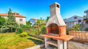 Un horno de piedra al aire libre con base de ladrillo, rodeado por un patio con baldosas de piedra.