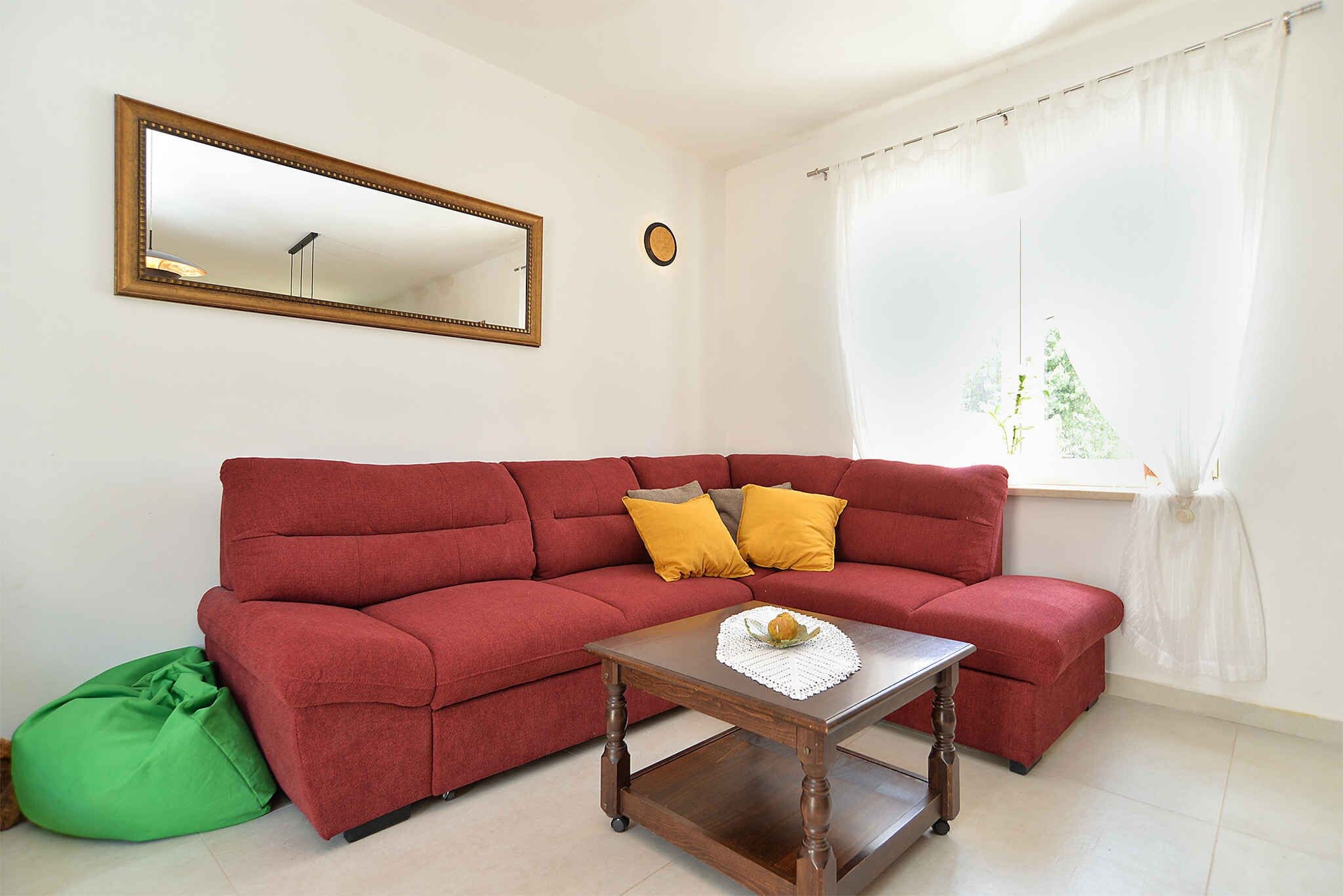 A red sofa with yellow cushions, a wooden coffee table with a white doily, and a green bean bag.