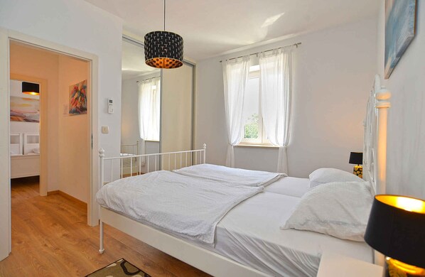 A bedroom with a single bed, a bedside table, a lamp, and a window with curtains.