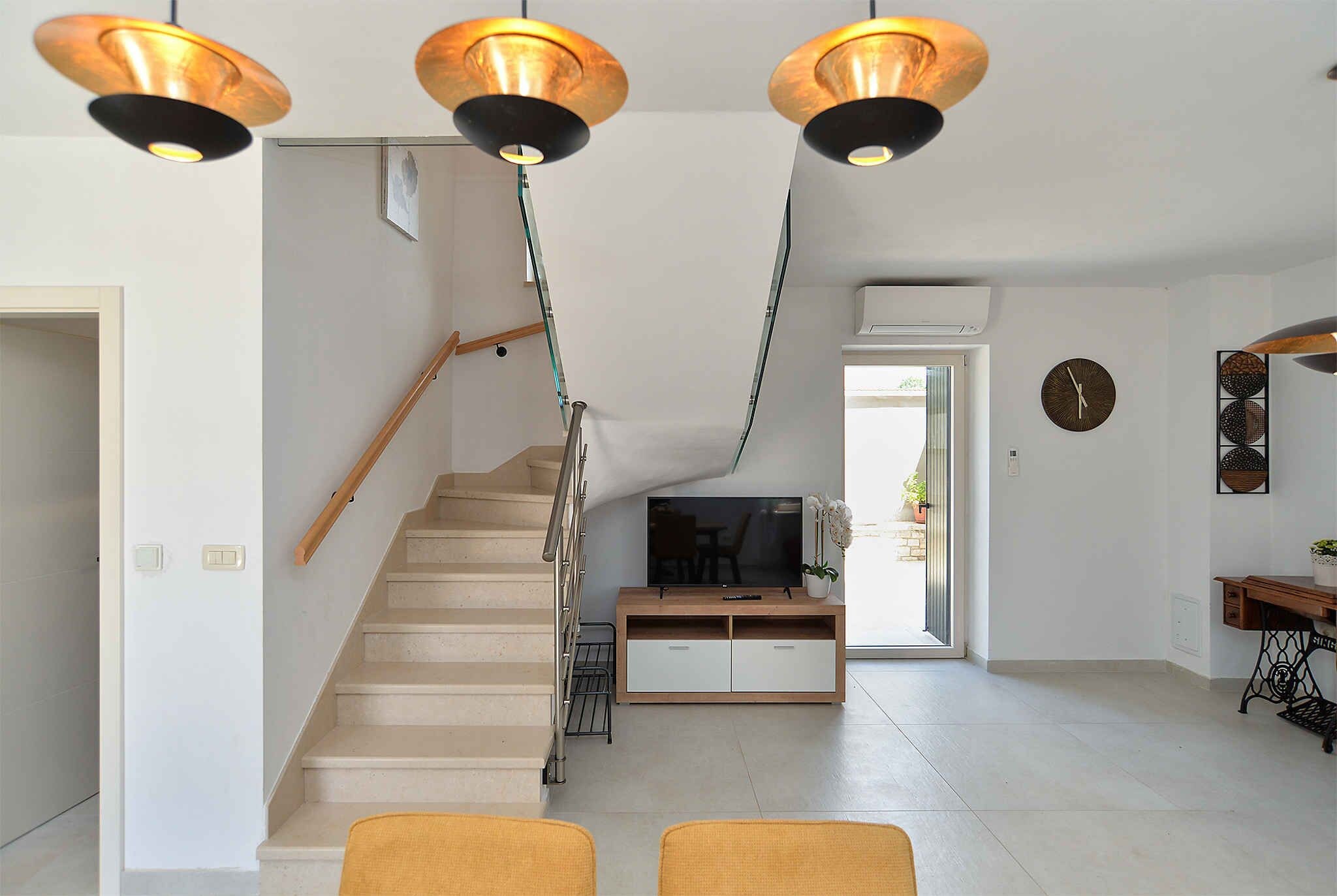 Ein modernes Interieur mit einer Treppe, einem Flachbildfernseher und einem Essbereich.