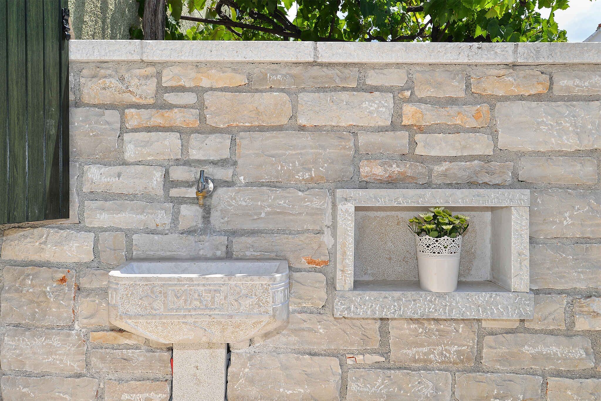 Una pared de piedra con un lavamanos integrado y una pequeña jardinera.