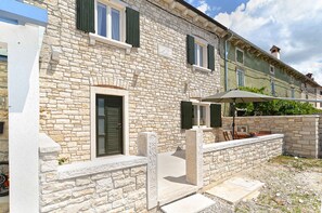 A stone building with a door, windows, and a small outdoor seating area with chairs and a table.
