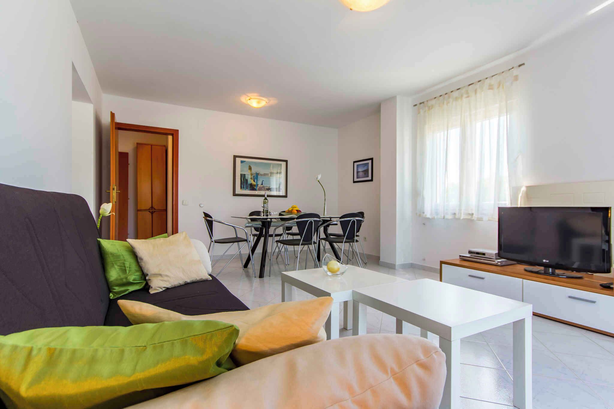 A modern living room with a sofa, dining table, chairs, and a television.
