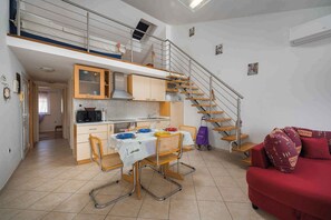 A compact living space with a kitchen, dining area, and a staircase to an upper level.