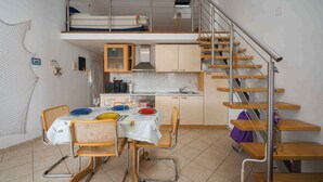 A compact kitchen with a dining area, a bunk bed, and a staircase. - Holiday apartment mit Klimaanlage und Balkon (Monterol)