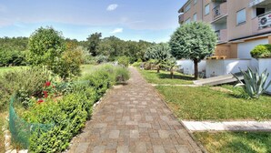 A paved pathway leading to a residential building with balconies, surrounded by greenery and a clear sky. - Holiday apartment mit Klimaanlage und Balkon (Monterol)