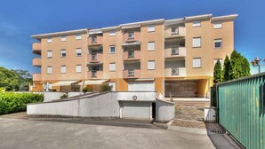A multi-story residential building with a flat roof, balconies, and a gated entrance. - Holiday apartment mit Klimaanlage und Balkon (Monterol)