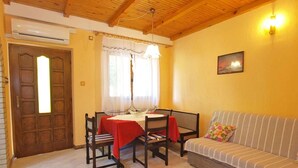 A cozy living room with a wooden ceiling, a dining table with chairs, a sofa, and a window with curtains. - Holiday apartment with air conditioning (Rovinj)