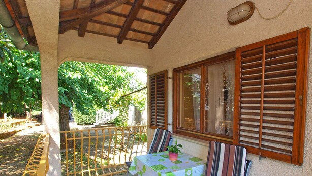 A covered patio with a table and chairs, a railing, and a view of greenery. - Holiday apartment with air conditioning (Rovinj)