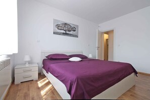 A bedroom with a bed, nightstands, a wall-mounted lamp, and a door. - Holiday apartment with air conditioning (Valbandon)