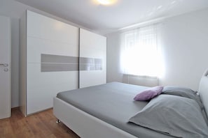 A bedroom with a bed, a wardrobe, and a window with curtains.