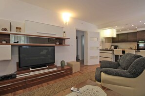 A modern living room with a flat-screen TV, a grey sofa, and a wooden entertainment unit.