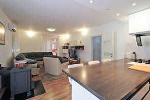 A modern living room with a sofa, a dining table, and a kitchen area with a stove.