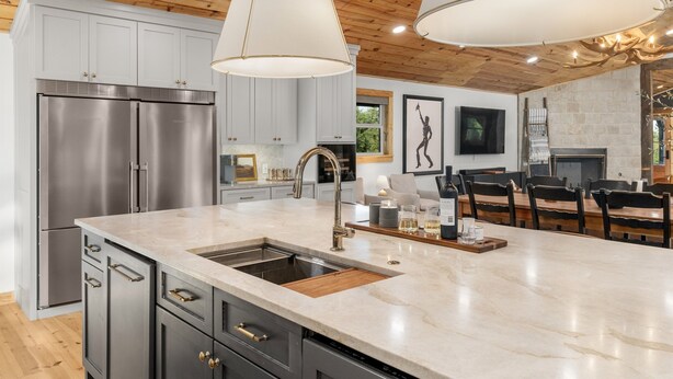 A modern kitchen with stainless steel appliances, a marble countertop, and wooden ceiling beams. - Main Cabin - The Hendo (Henderson)