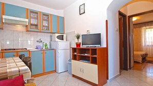 Een compacte woonruimte met een kitchenette, een eethoek en een tv-meubel.