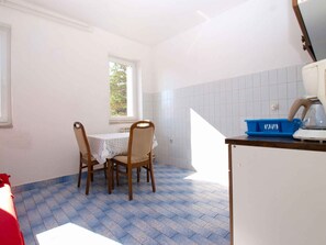 Uma cozinha com mesa, cadeiras, uma janela e uma cesta azul no balcão.
