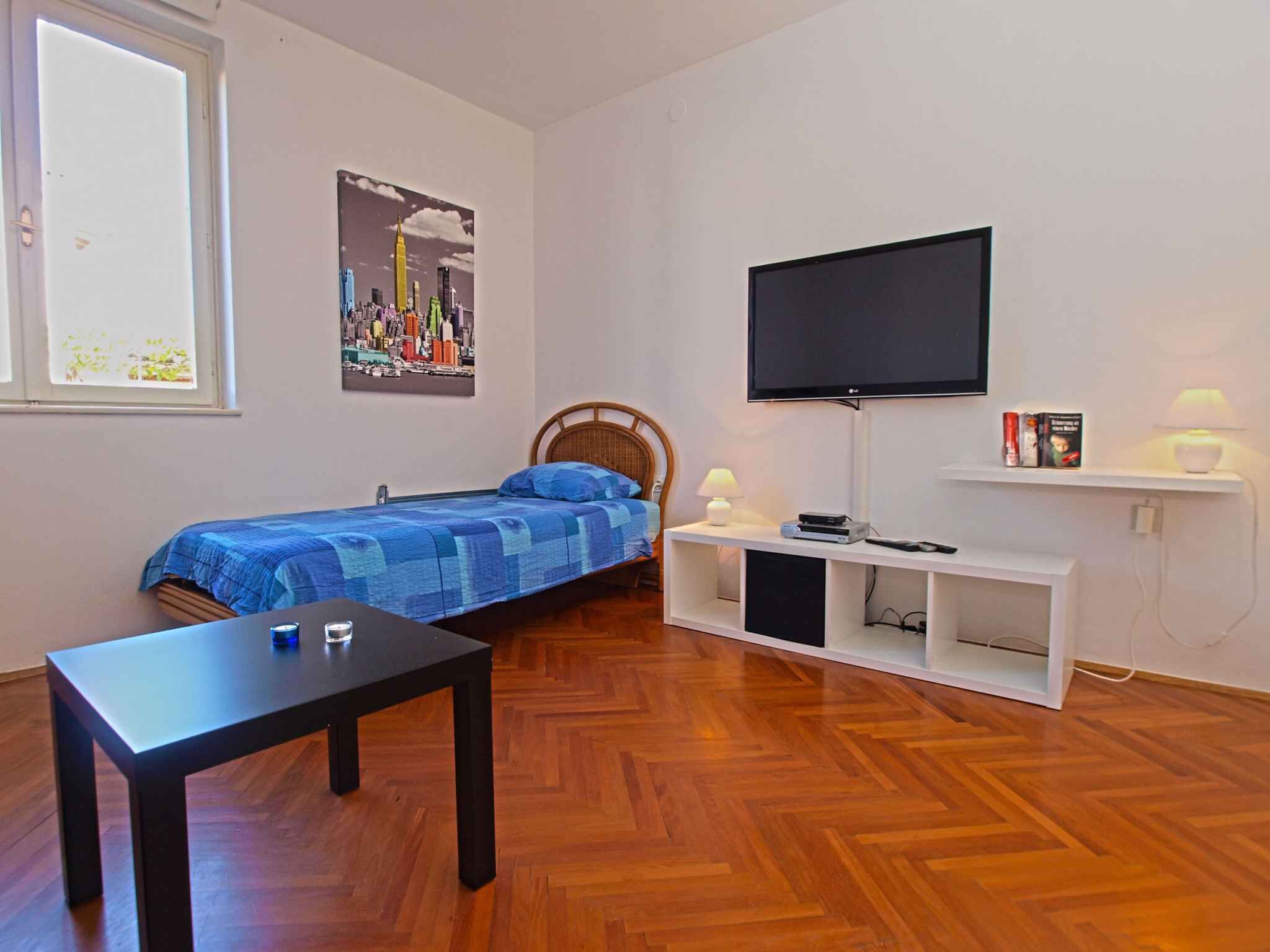 Une chambre avec un lit, une télévision, une table et une bibliothèque.