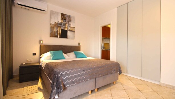 A bedroom with a bed, nightstand, and a wardrobe. - Holiday apartment with air conditioning (Premantura)