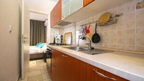 A compact kitchen with wooden cabinets, a sink, and a countertop. - Holiday apartment with air conditioning (Premantura)