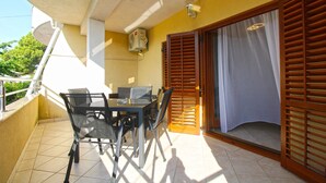 A balcony with a table and chairs, a ceiling fan, and a sliding door with a curtain. - Holiday apartment with air conditioning (Premantura)