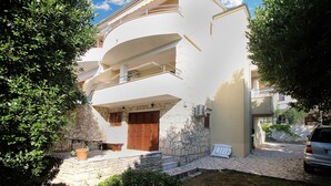 A multi-story building with a stone facade, balconies, and a car parked in front. - Holiday apartment with air conditioning (Premantura)