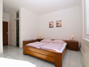 A bedroom with a wooden bed, two bedside tables, a door, and two wall-mounted flower paintings.