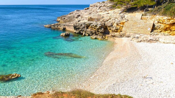 A coastal beach with clear turquoise water, rocky terrain, and sparse vegetation. - Holiday apartment with air conditioning (Pula)