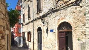 A narrow cobblestone street with stone buildings, wooden shutters, and a sign indicating a hotel. - Holiday apartment with air conditioning (Pula)