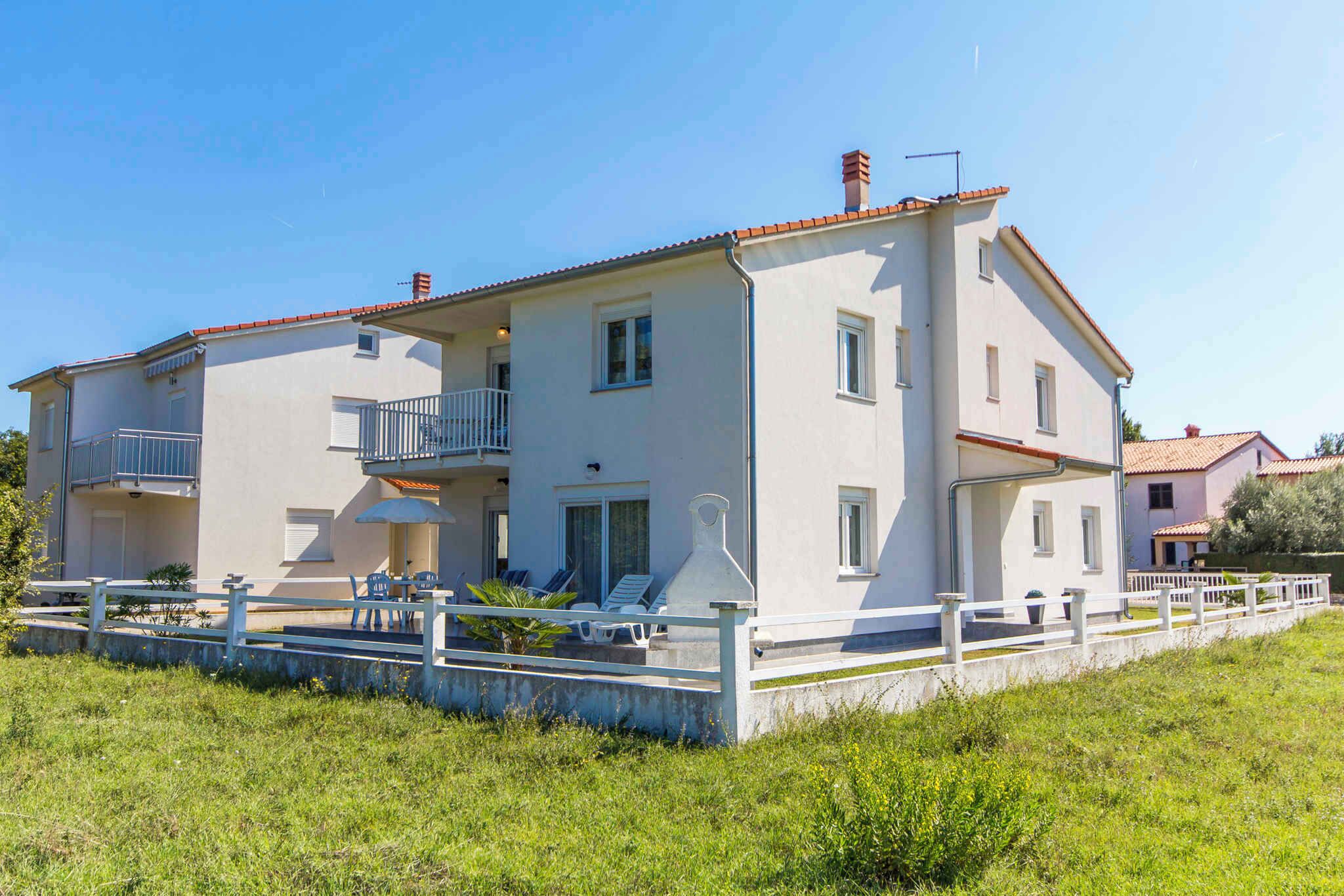 A two-story house with a balcony, a small garden, and a white fence.