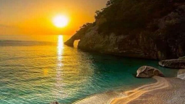 A coastal sunset with clear skies, calm waters, and rocky cliffs. - Mountain Relaxation  (Baunei)