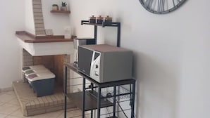 A kitchen with a built-in oven, a sink, and a countertop. There is a shelf with jars and a clock on the wall. - Mountain Relaxation  (Baunei)