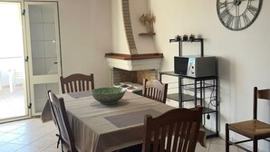 A dining area with a table, chairs, a green bowl, a clock, and a television on a stand. - Mountain Relaxation  (Baunei)