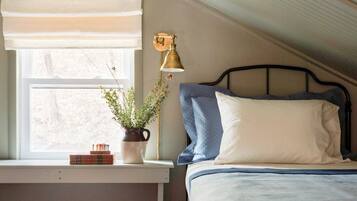 A bedroom with a bed, a window with a view, a lamp, and a plant on the windowsill.