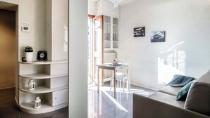 A modern, well-lit room with a dining area, a sofa, and a ceiling fan. - La Finestra sul Lago (Cernobbio)
