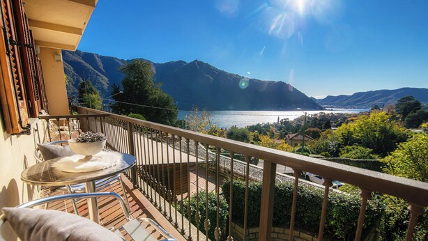 A balcony with a table and chairs, overlooking a lake and mountains. - La Finestra sul Lago (Cernobbio)