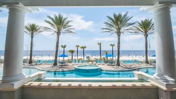 Ein Poolbereich mit Palmen und Blick auf den Strand.