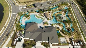 Vista aerea di un resort con diverse piscine, una strada e vegetazione circostante.