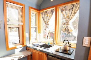 Een koelkast, een kookplaat, een waterkoker, kookgerei, borden en bestek