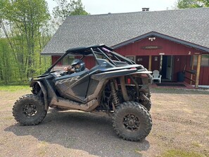 Ein Polaris RZR Geländefahrzeug vor einem rustikalen Gebäude mit dem Schild "Piperhaus".