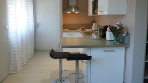 Eine moderne Küche mit Barhocker, Edelstahlgeräten und einer Vase mit Blumen auf der Arbeitsfläche.