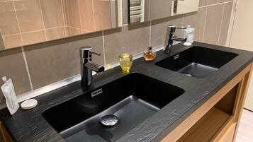 A bathroom with two sinks, a mirror, and a towel rack.