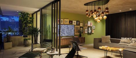 A modern living room with a sofa, chairs, a coffee table, and a large TV screen.