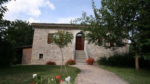 A stone building with a central entrance, a small tree, and a paved pathway leading to the entrance. - Rossini Apartment (Urbania)