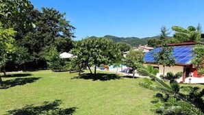 A residential area with solar panels on the roofs, surrounded by greenery and hills in the background. - Rossini Apartment (Urbania)