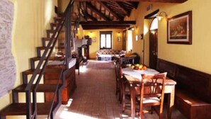 A rustic interior with a wooden staircase, a dining area with a table and chairs, and a bench. - Rossini Apartment (Urbania)