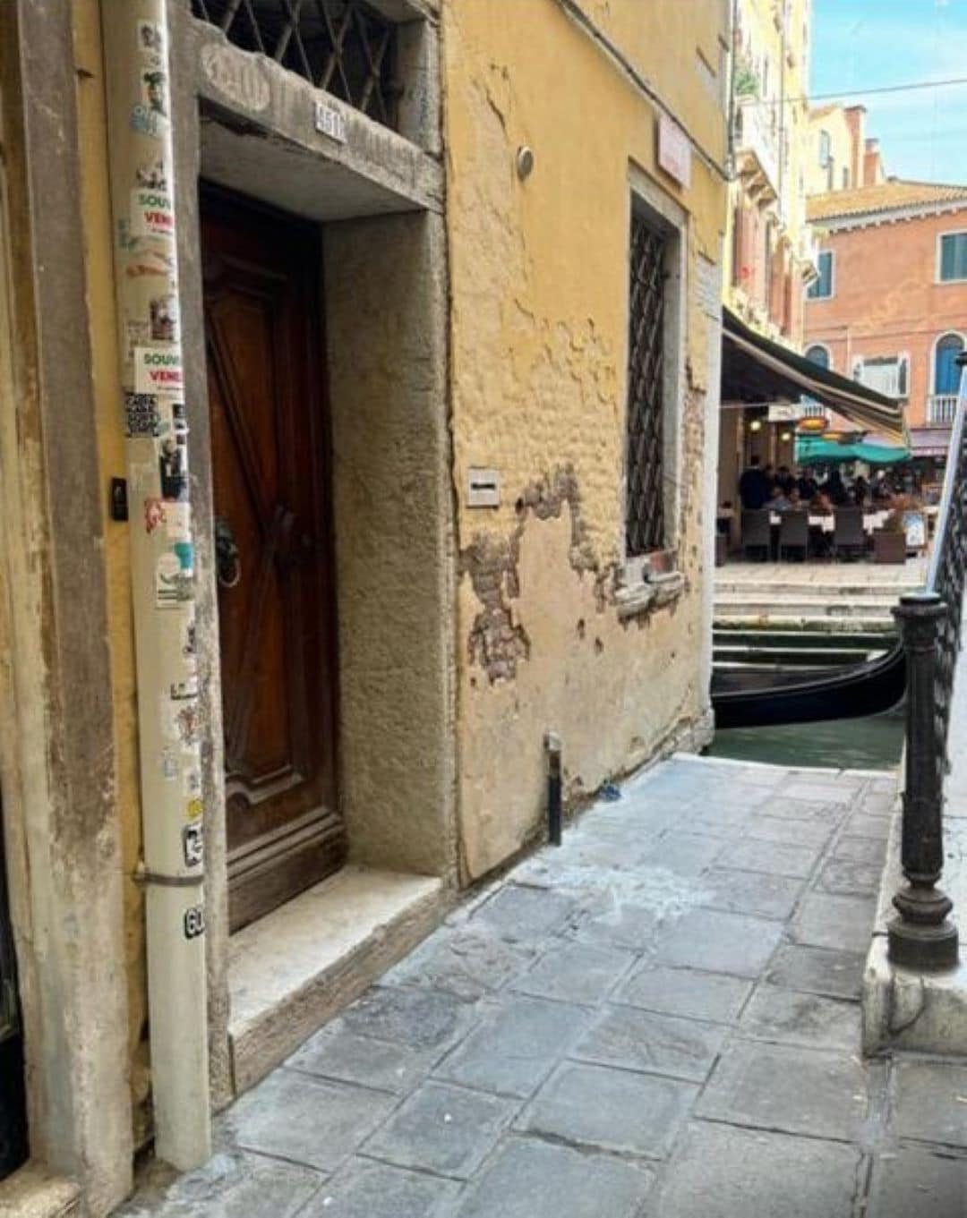 A narrow street with a building featuring a wooden door and a window.