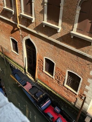 A canal-side building with a row of windows and a boat docked in front. - Ca' San Zaccaria (Venice)