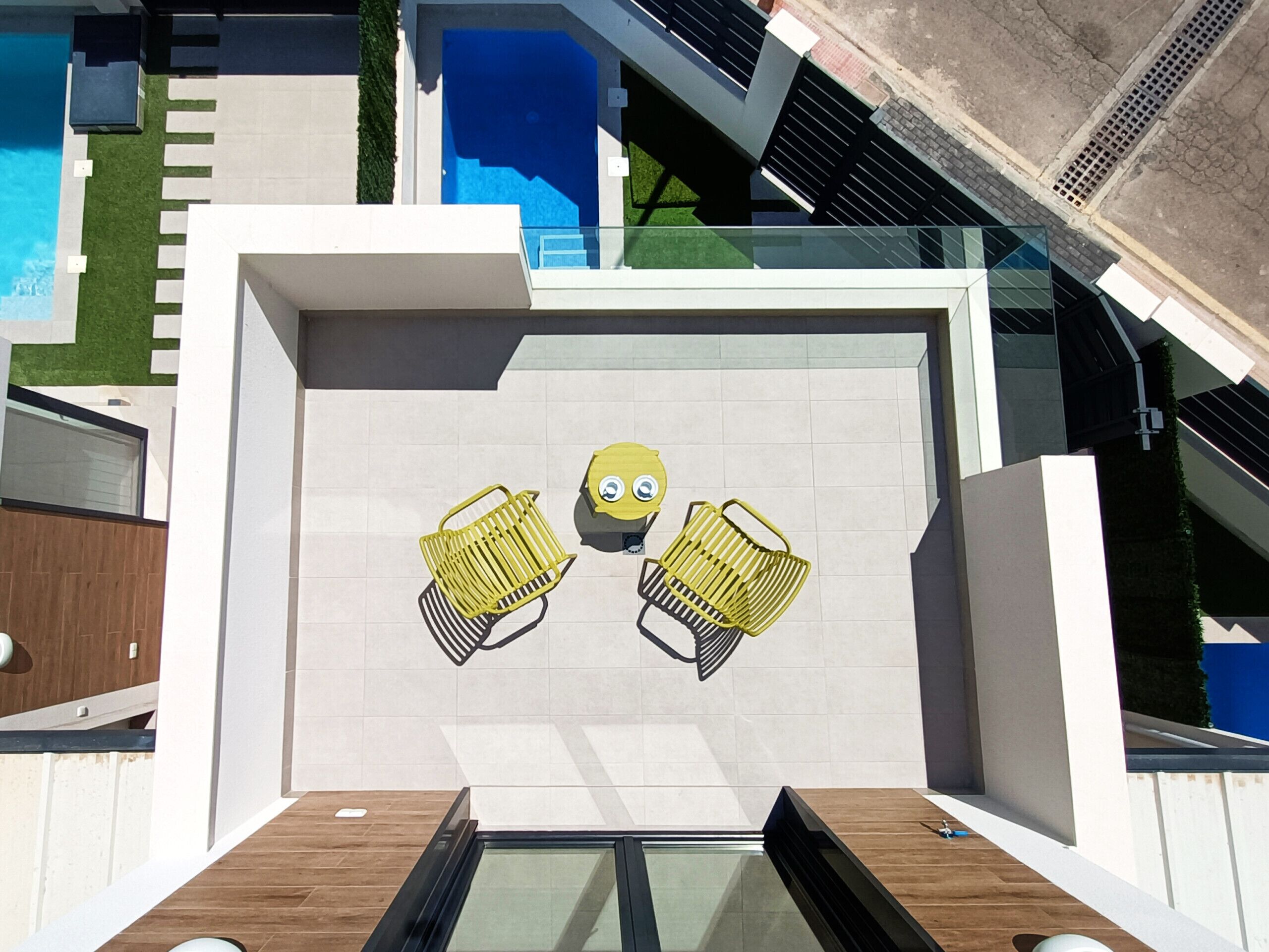 Een moderne buitenzitplek met twee gele stoelen en een Minion-personage.