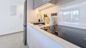 Een moderne keuken met een roestvrijstalen koelkast, een inbouwoven en een groot raam dat zorgt voor daglicht.